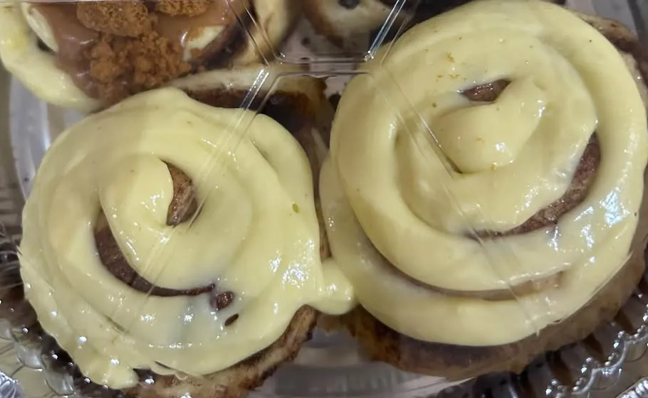 Two frosted cinnamon rolls with visible cinnamon swirls, seen from above